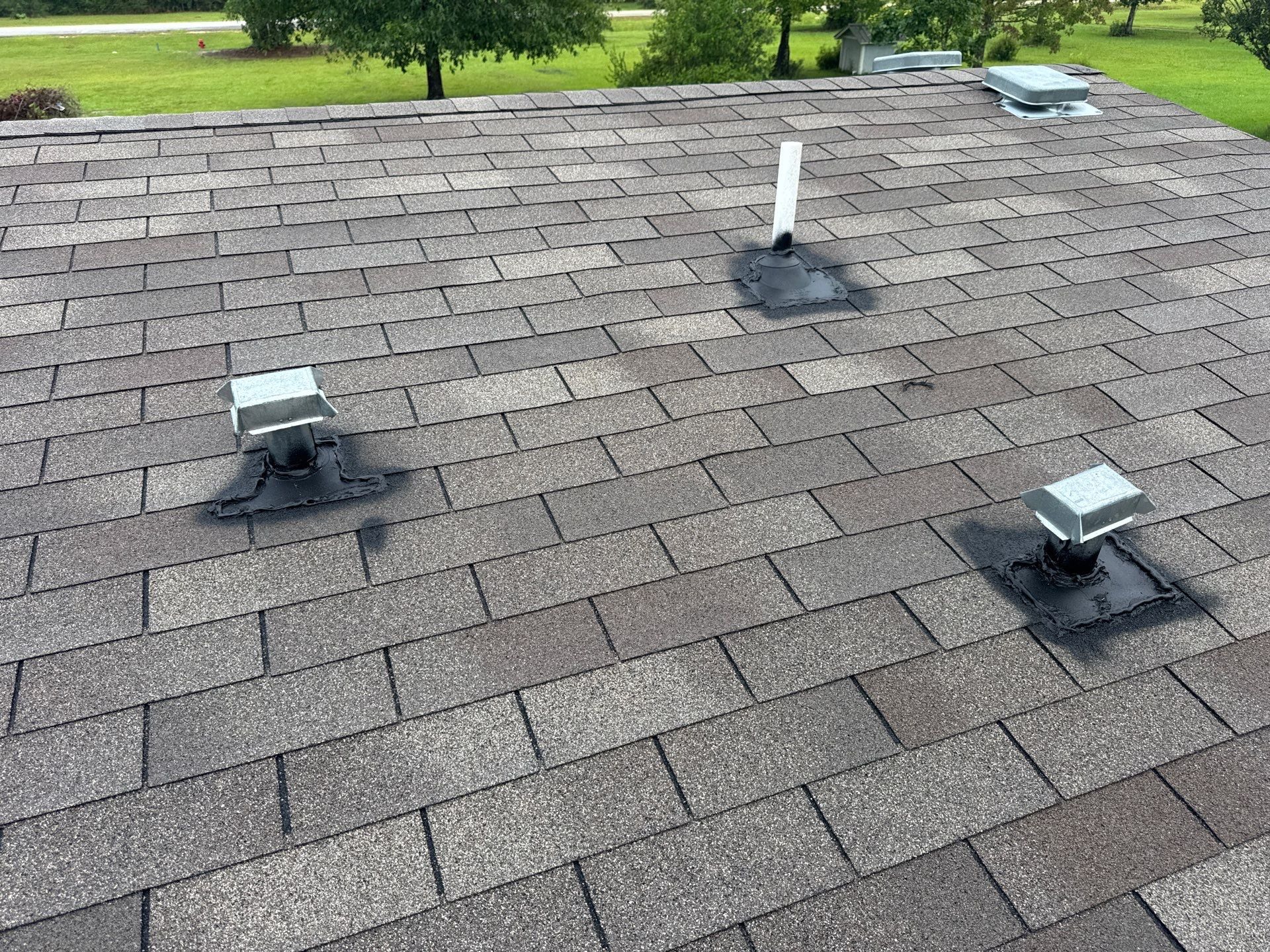 Black vent boots around plumbing vent pipes on a shingled GD Construction roof