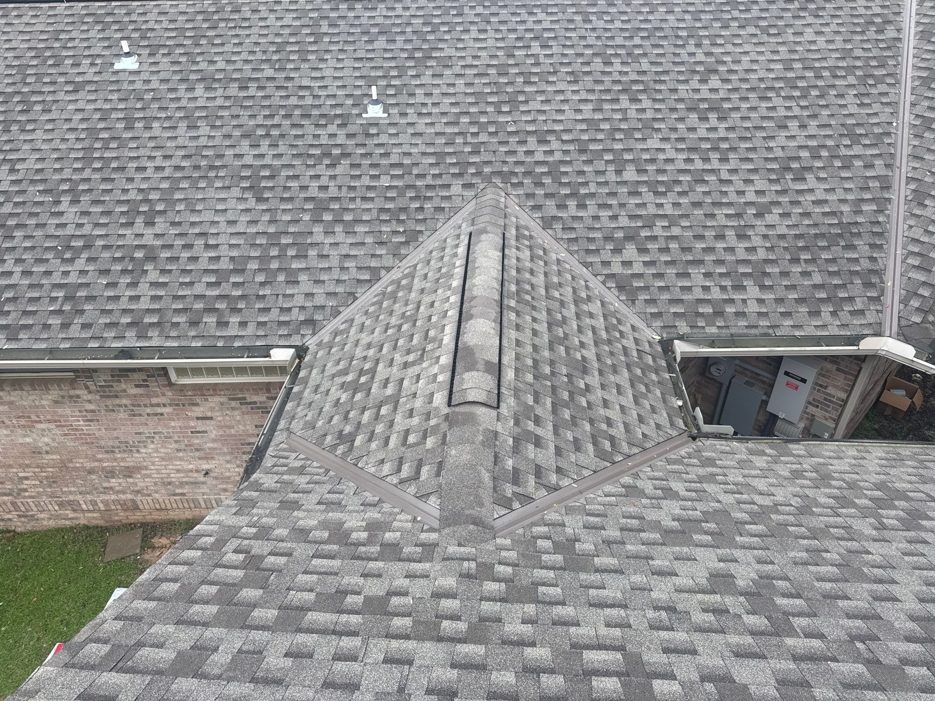 Finished architectural asphalt shingle hip roof with clean hips, cut valleys, and ridge cap