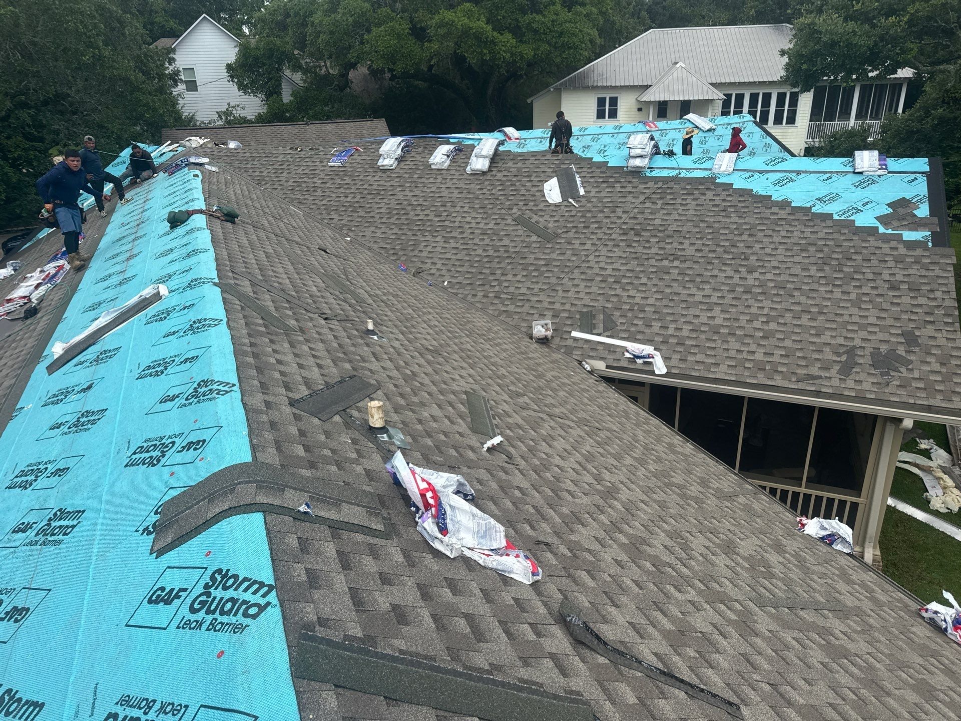 GD Construction crew working both slopes of a hip roof during a Gulf Coast re-roof